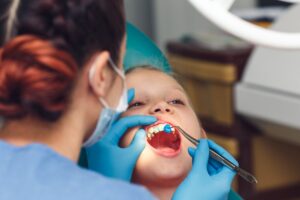 Child receiving dental examination, pediatric dentist performing gentle cleaning and monitoring oral health, emphasizing preventive care and comfort.