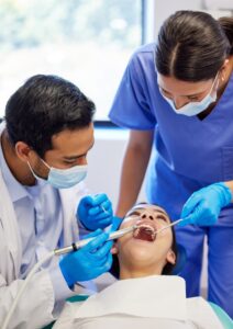Dental professionals performing a preventive dental cleaning on a patient in a clinical setting, emphasizing oral health and hygiene.
